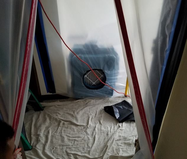 Plastic containment with a fan port pulling air out of a sealed room